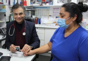 Dr Vipin Goyal (left) demonstrating how to conduct a blood glucose test