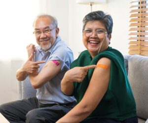 Older couple happily showing off their vaccination bandaids.