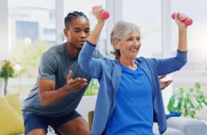 exercise physiologist with older female client using dumbbells for strength training